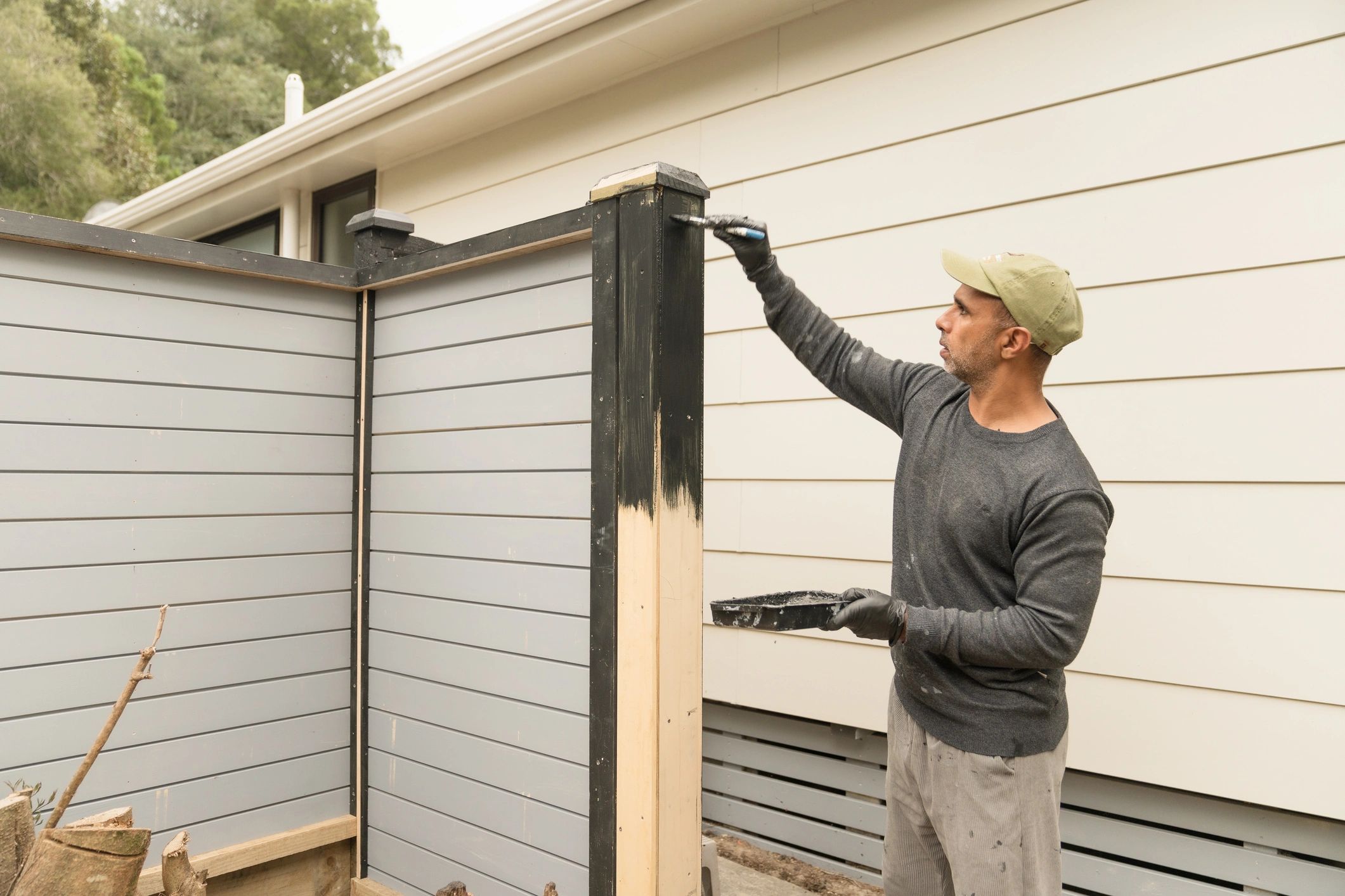 Worker staining a wood fence with a brush