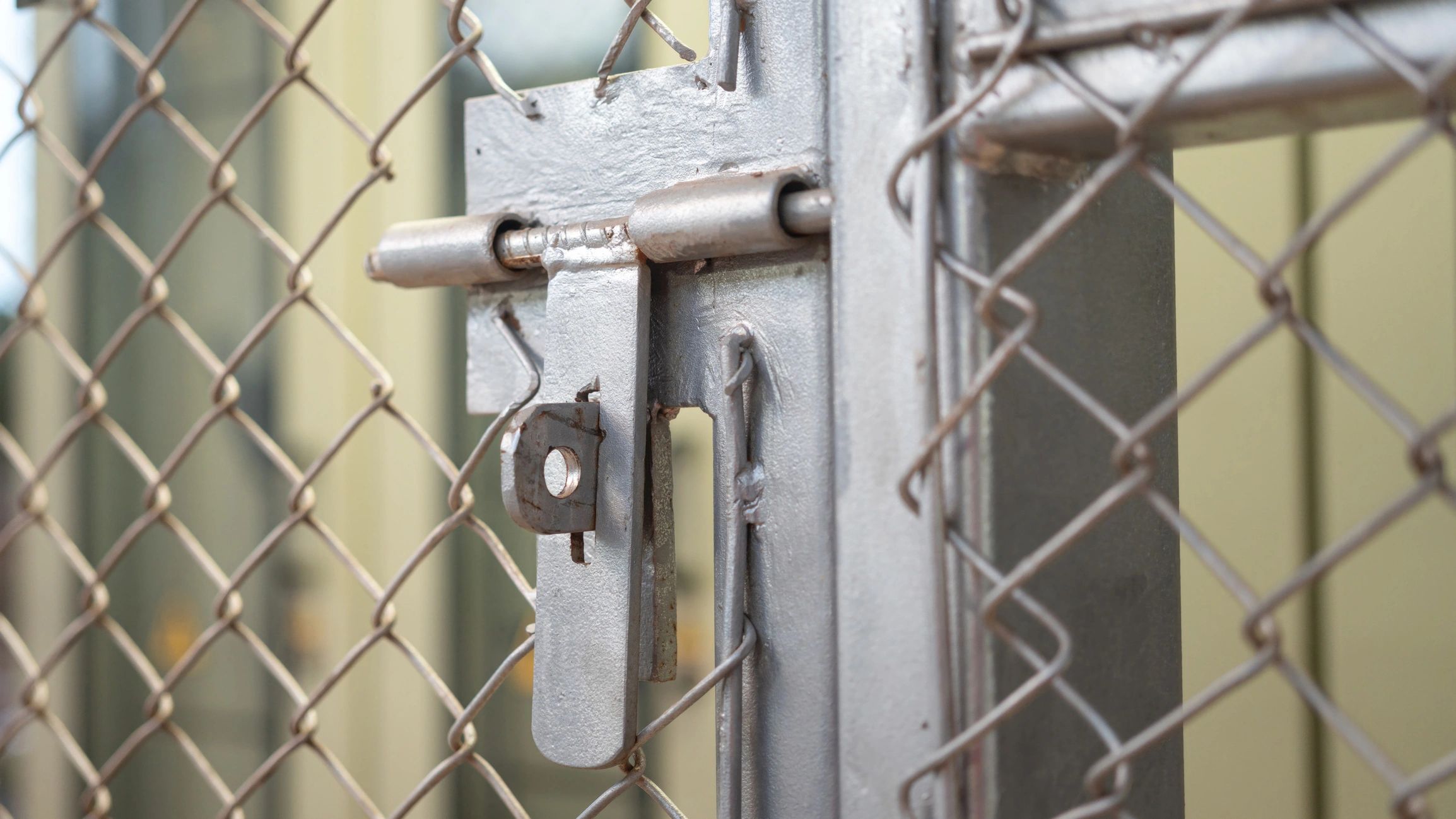 Close-up of a chain link gate latch and bolt hardware