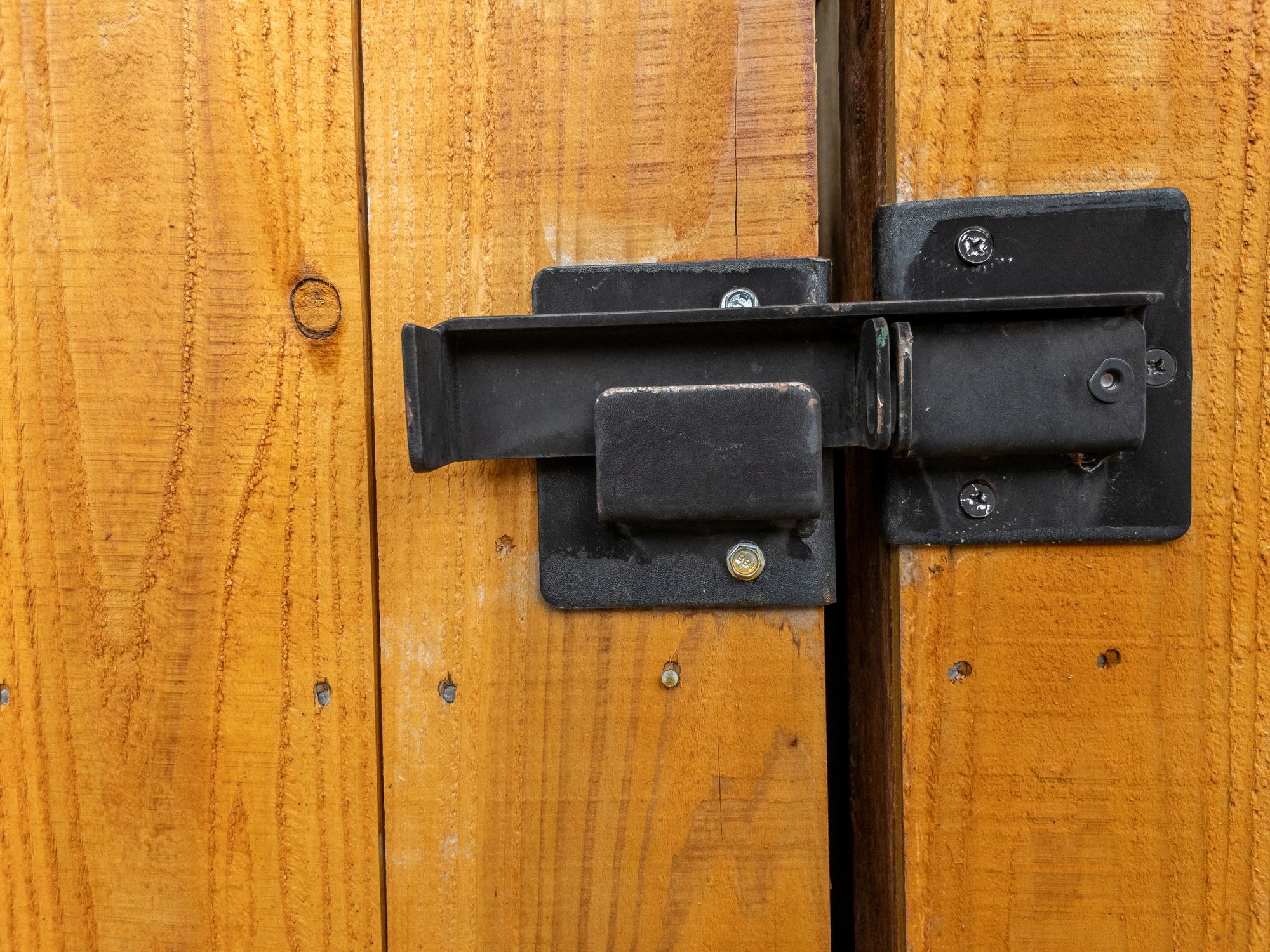 Black metal latch on wooden gate