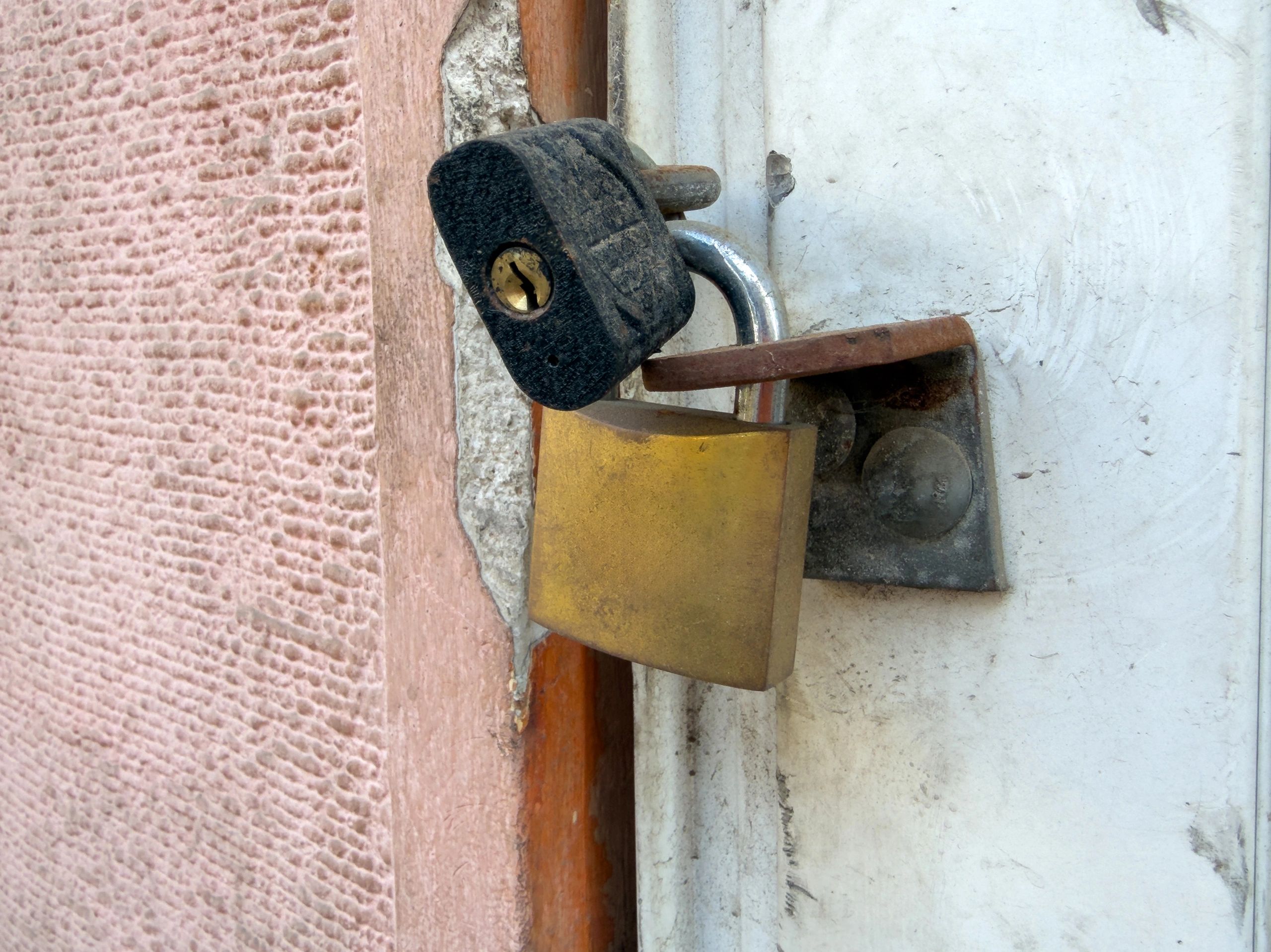 Close-up of a latch and lock hardware on a gate/door surface
